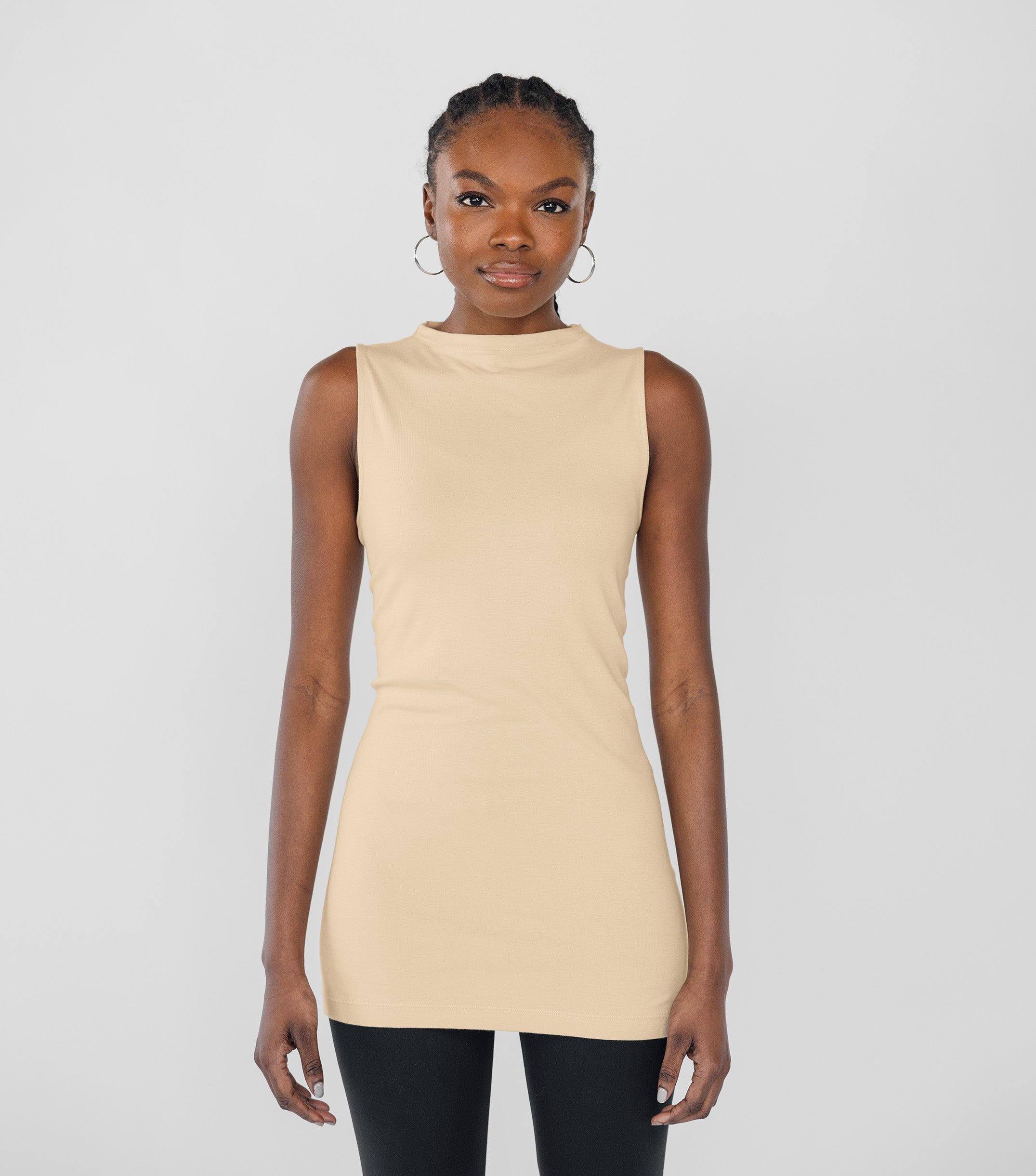 Woman wearing a beige sleeveless top against a plain background