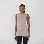 Woman wearing a beige sleeveless top and black leggings on a white background