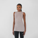 Woman wearing a beige sleeveless top and black leggings on a white background