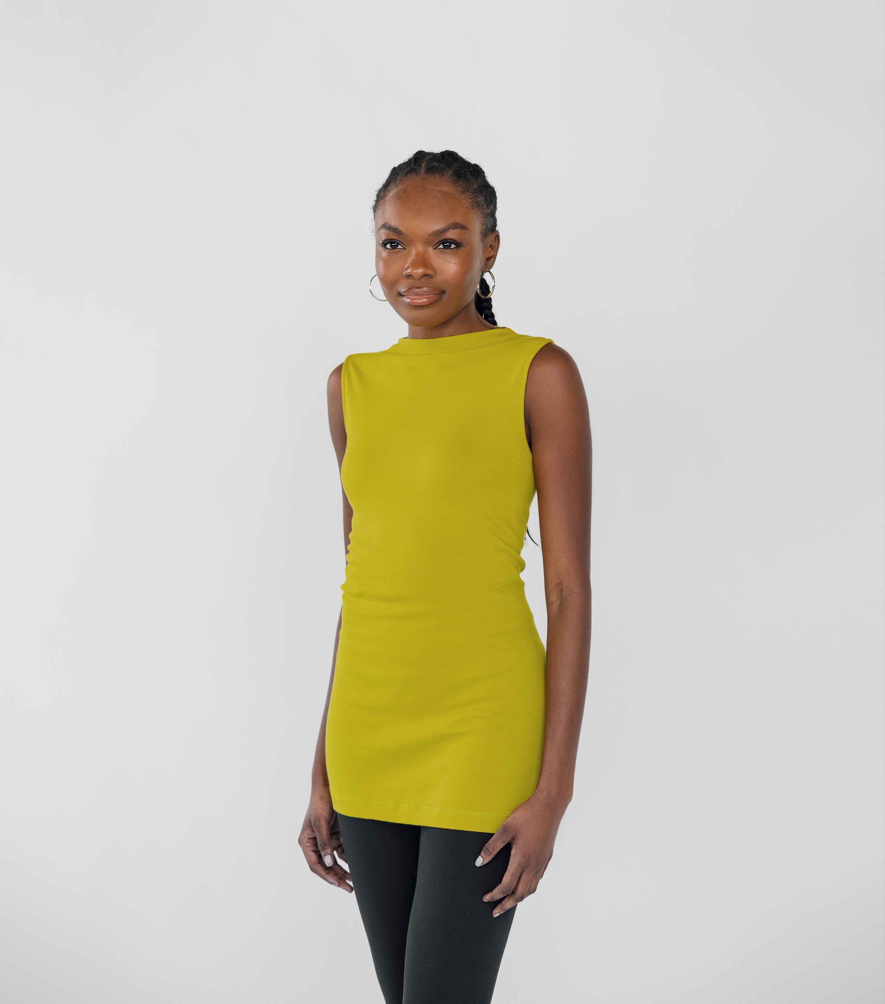 Woman wearing a sleeveless citrine yellow top on a white background