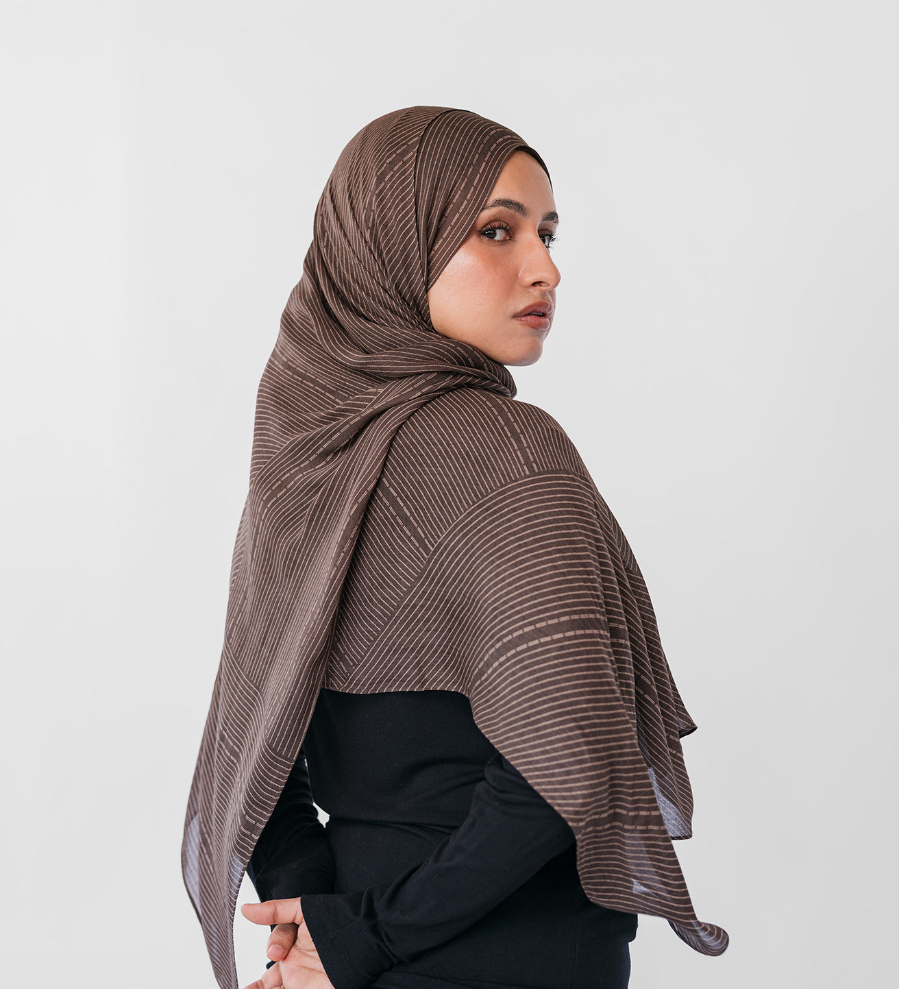 Woman wearing a brown striped hijab against a white background