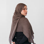 Woman wearing a brown striped hijab against a white background