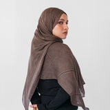 Woman wearing a brown striped hijab against a white background