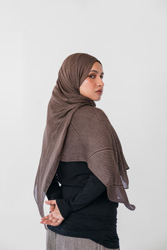 Woman wearing a brown striped hijab against a white background