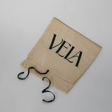 Beige drawstring bag with 'VELA' branding on a light gray background