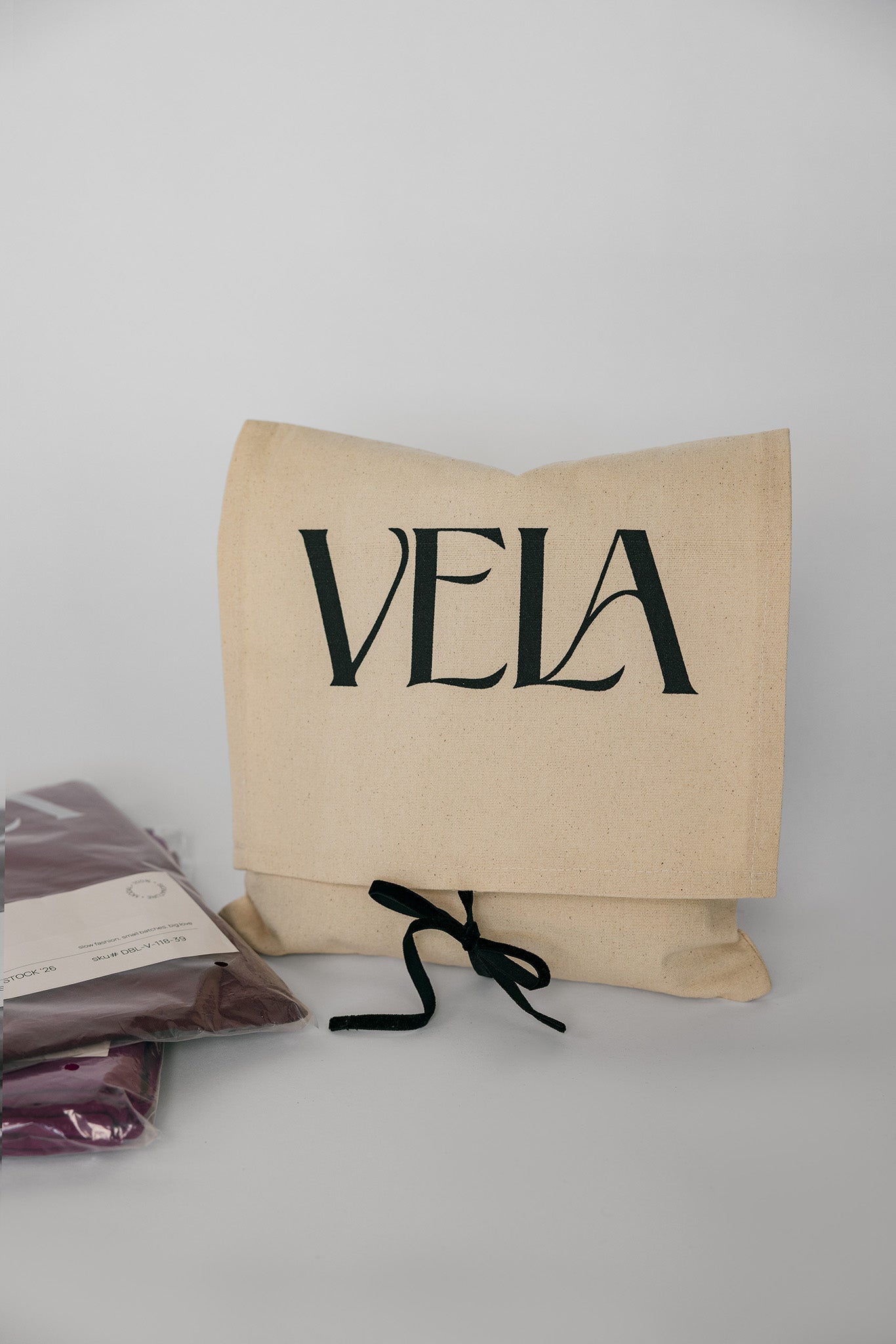 Beige pillow with 'VELA' branding on a gray background