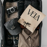 Open suitcase with clothing, a cap, and a camera on a light gray background