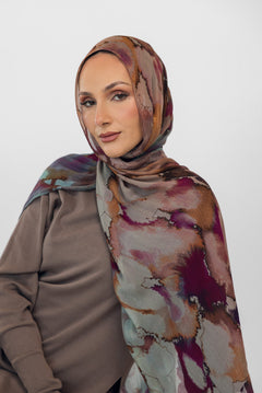 Woman wearing a watercolor floral patterned hijab and brown top against a white background