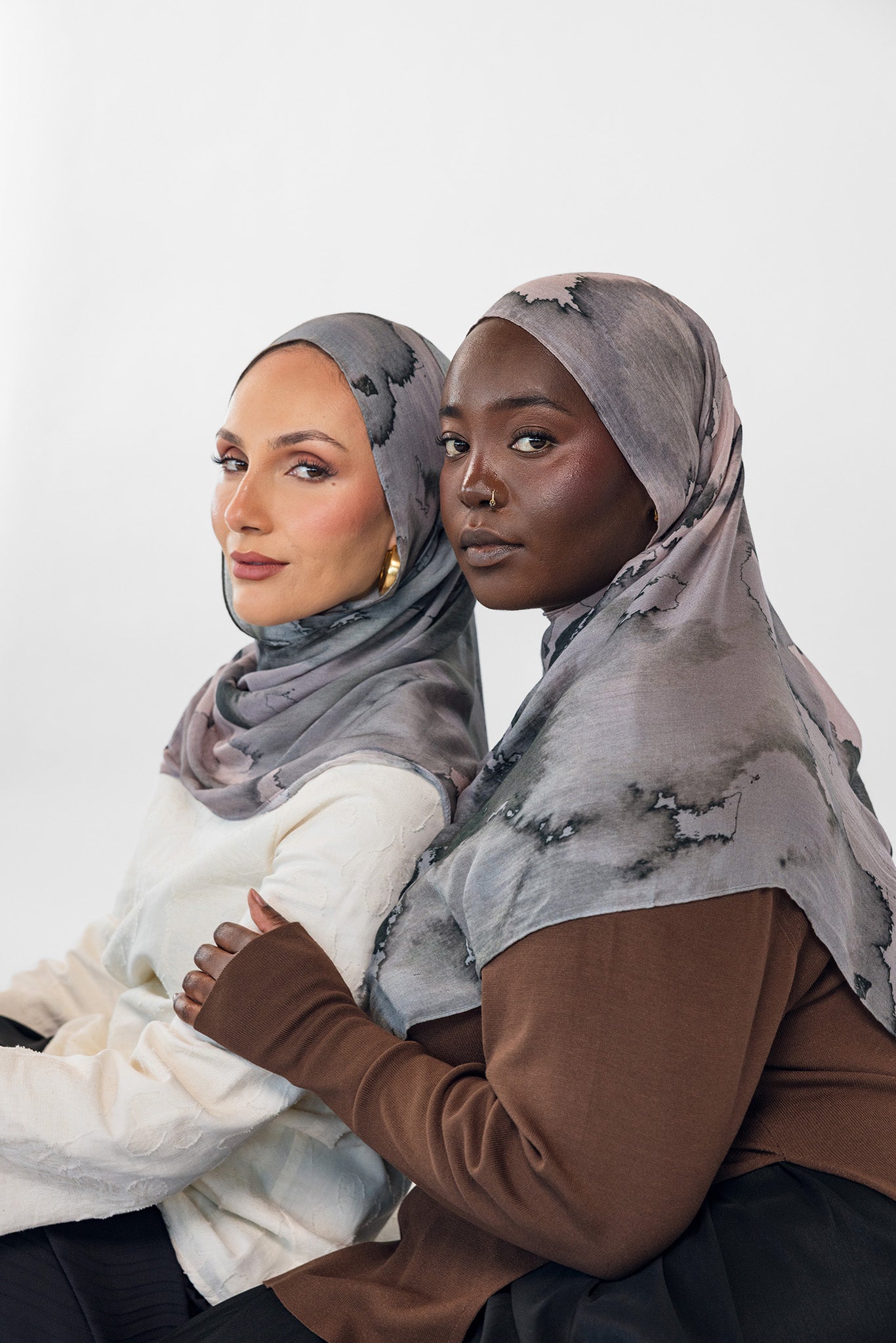 Two women wearing watercolor stone hijabs against a white background