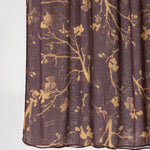 A close-up of a sheer pleated fabric panel, likely a curtain, in a dark plum purple color with a metallic gold branch and floral pattern, shown against a plain white background.