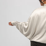 Person wearing a beige satin shirt on a light gray background