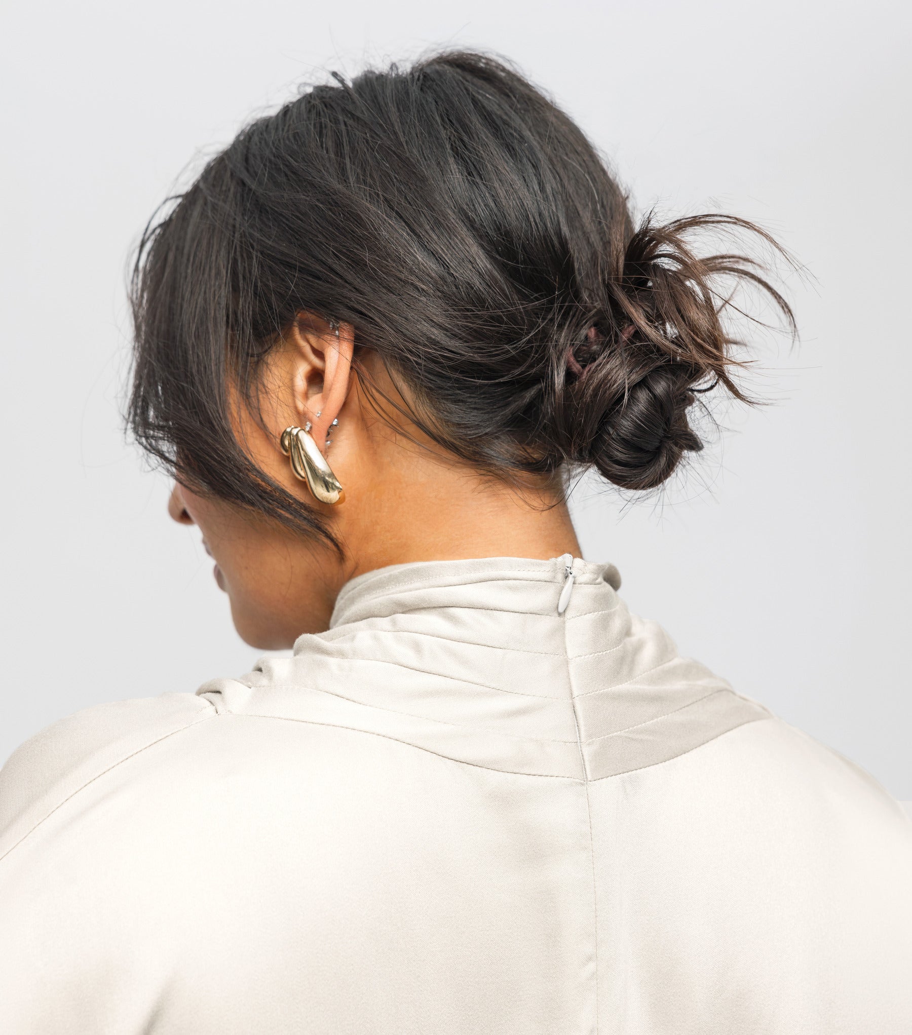 Person wearing a beige jacket with a plain background