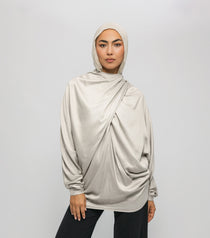 Woman wearing a beige hijab and long-sleeve top against a white background