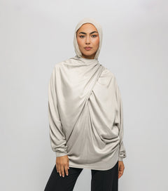 Woman wearing a beige hijab and long-sleeve top against a white background