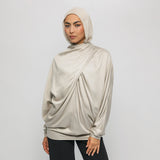 Woman wearing a beige hijab and top against a white background