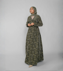 Woman wearing a green patterned abaya on a plain background