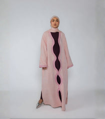 Person wearing a pink and magenta abaya with a white background