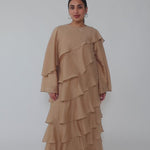 Woman wearing a beige layered dress on a gray background