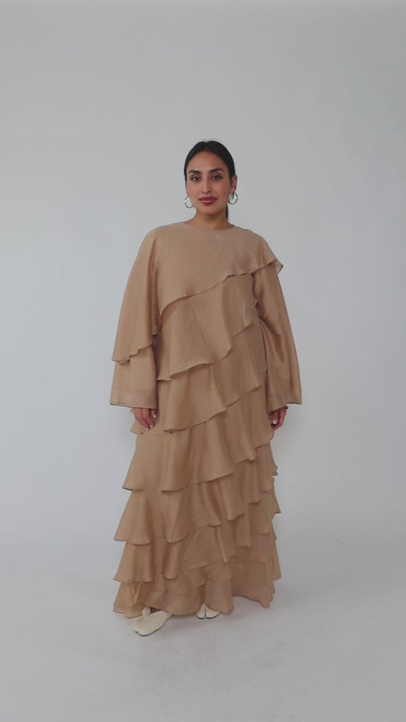 Woman wearing a beige layered dress on a gray background