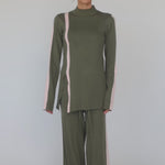 Model styled in green matching top and pants with pink stripe. 