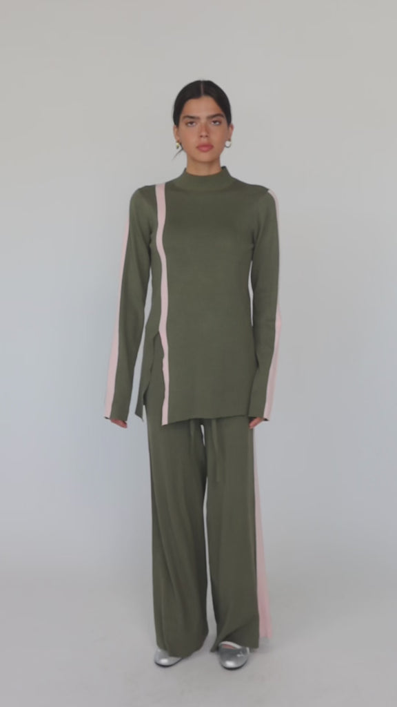 Model styled in green matching top and pants with pink stripe. 