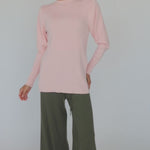 Model styled in a pink knit top with slits paired with green pants 