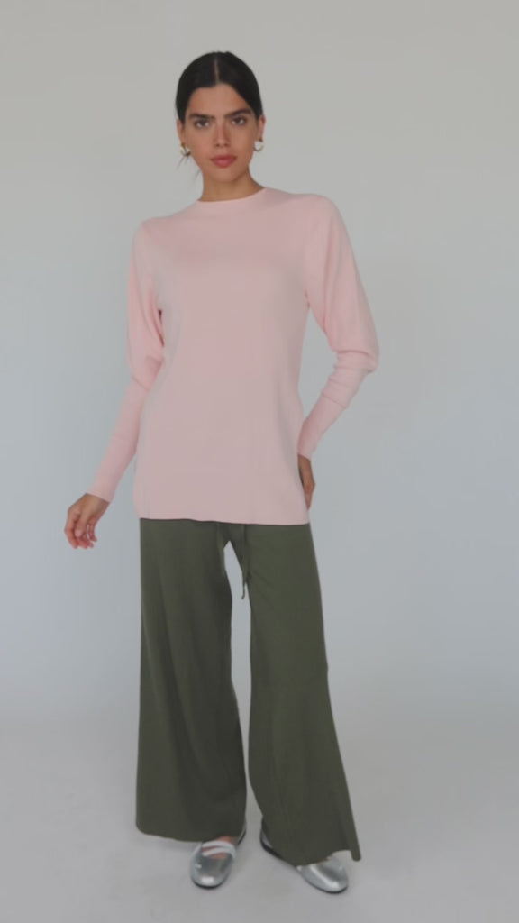 Model styled in a pink knit top with slits paired with green pants 