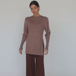 Model styled in long sleeve beige top with brown pants.