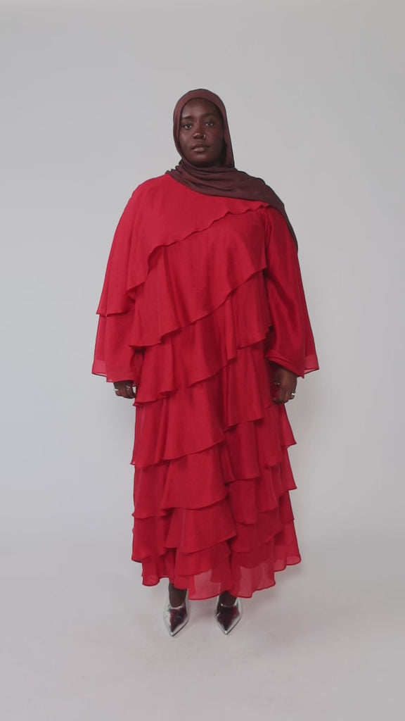 Woman wearing a red layered dress on a gray background