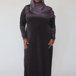 Woman wearing a black long-sleeve dress against a gray background