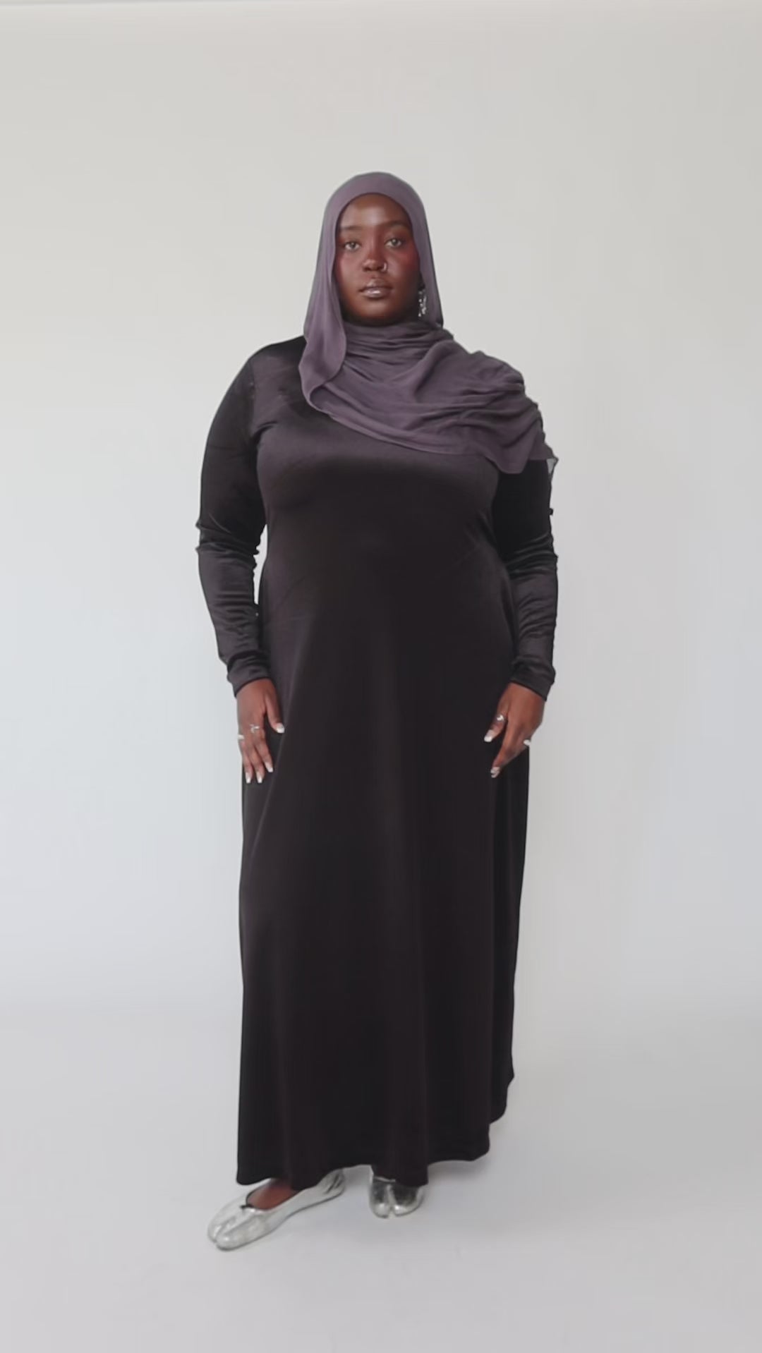 Woman wearing a black long-sleeve dress against a gray background