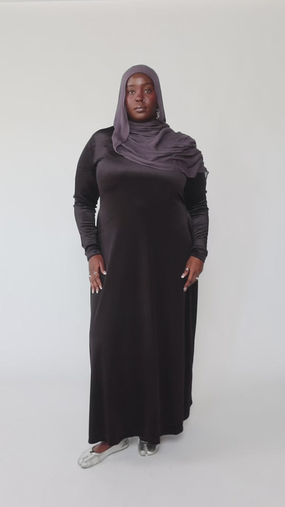 Woman wearing a black long-sleeve dress against a gray background