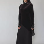 Woman wearing a black abaya and hijab on a gray background