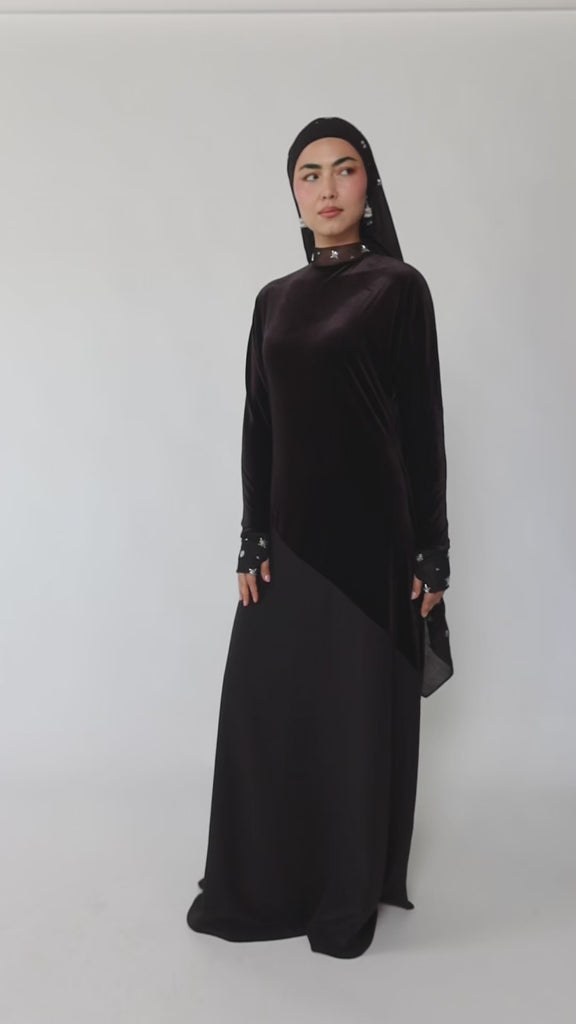 Woman wearing a black abaya and hijab on a gray background
