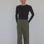 Model styled in black top and green pants with pink stripes. 