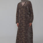 Woman wearing a green jacquard patterned abaya on a gray background