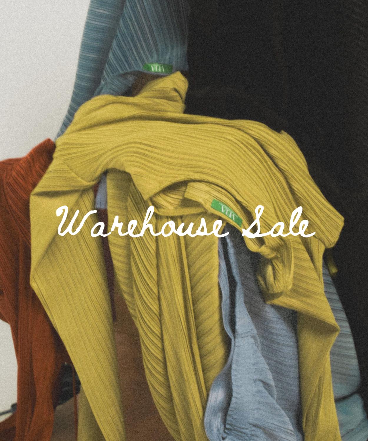 A clothing rack displaying multiple garments in different colors, including light blue, gray, rust red, tan, olive green, and black, with a large white script overlay reading 'Warehouse Sale'.